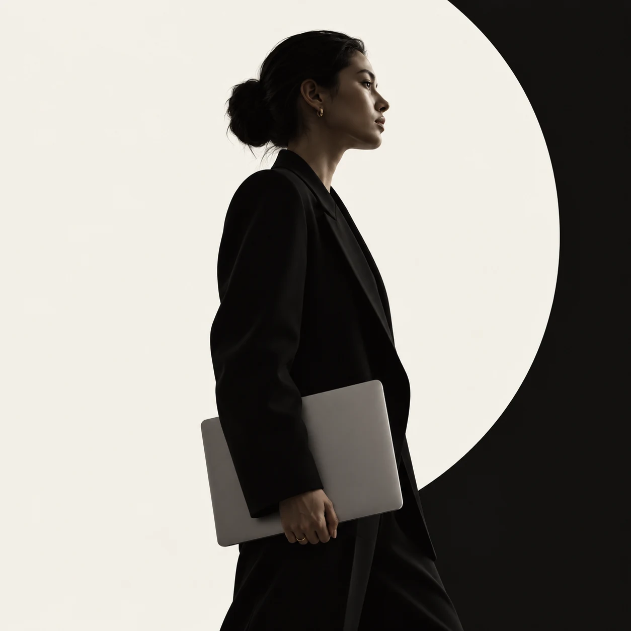 A silhouetted figure holding a laptop against a circular light