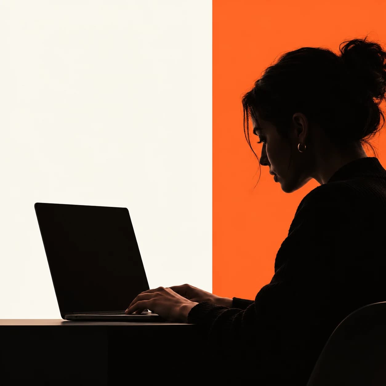 A creative working at a laptop against a bright orange panel