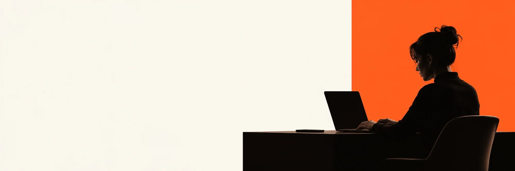 A silhouetted creative at a laptop against cream and vivid orange architectural panels